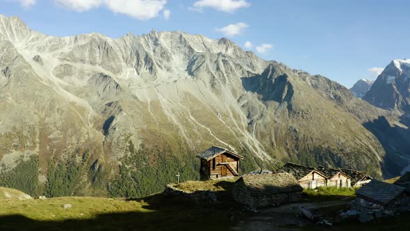 Flying behind small "alpage" chalets with high mountain peaks in the backgroundAutumn colors in Aro alt