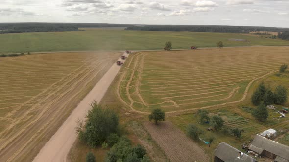 Aerial: a Group of Combine Harvesters Driving Along a Country Road Near To Perform Work