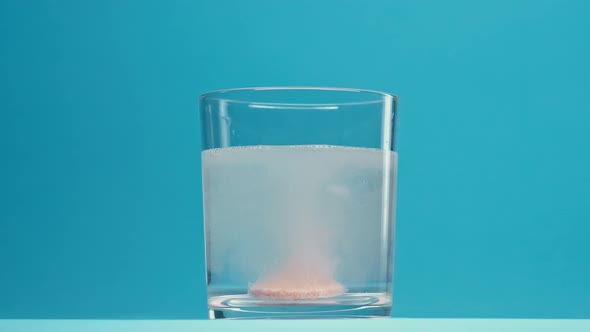 Sparkling Vitamin Pill Drops in Glass of Water