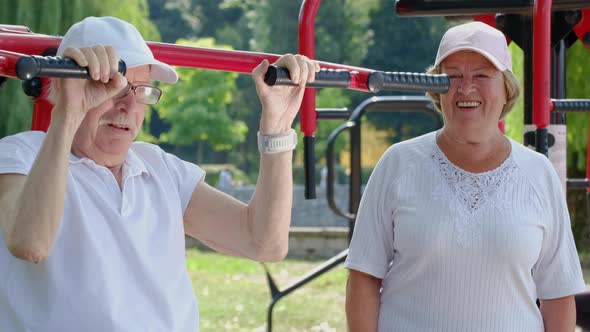 Happy retired couple playing sports outdoors on a beautiful sunny summer day. alt