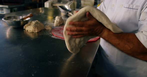 Chef patting pizza dough with the help of his hand 4k alt