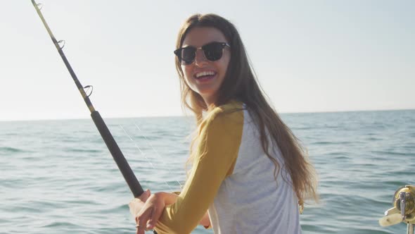 Side view of a teenage Caucasian girl fishing on boat and looking