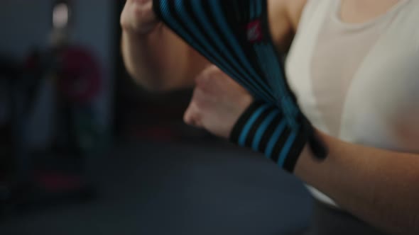 A Woman Wrapping Her Hands in Bandages Before a Bench Press Lying in the Gym alt