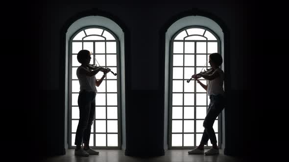 Girl Plays the Violin in the Evening Against the Background of a Window alt