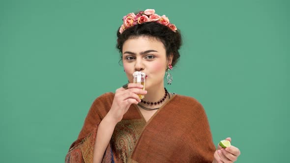 Portrait of Charming Happy Woman with Thick Eyebrows and Red Lips Drinking Tequila with Lime alt