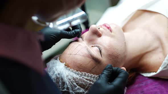 Permanent Makeup Cosmetologist Master Takes Measurements for the New Shape of the Eyebrows of Model alt