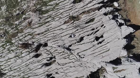 Caucasian person laying down on rugged rough landscape looking up at sky, spinning descending aerial alt