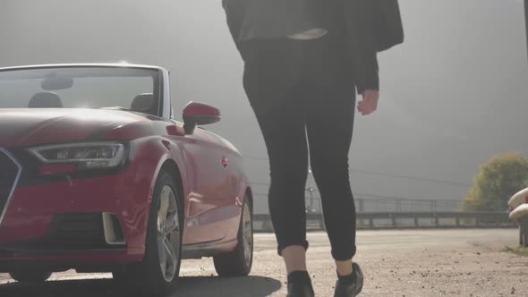 Girl Gets Into Red Cabriolet at Mountains. Summer Vacation Mood.