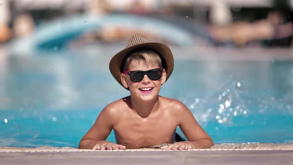 Portrait Laughing Cute Male Kid Vacationer Posing at Swimming Pool Surrounded By Water Splash alt