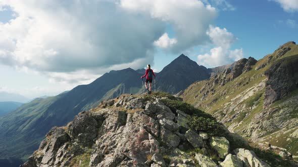 Aerial view of mountain landscape with girl hiker on top alt