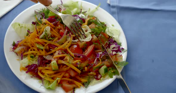 Lady Holds Fork and Eats Delicious Fresh Vegetable Salad alt
