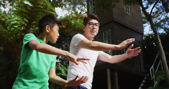 Happy asian fother exercising in garden with sonr, practicing tai chi together alt