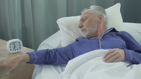 Old Man Hearing Alarm Clock, Reluctant to Wake Up, Lack of Sleep and Energy alt