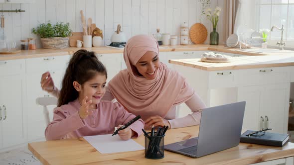 Muslim Mother And Daughter Making Video Call Via Laptop Indoor alt