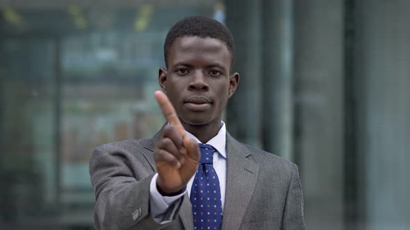 Refusal,negativity. Black african man in the street making NO with finger alt