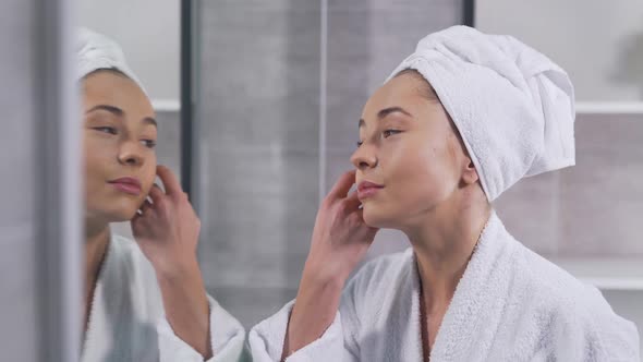 Girl Touches Her Face and Looks in the Mirror alt