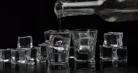 Pouring Up Two Shots of Vodka From a Bottle Into Glass Black Background alt