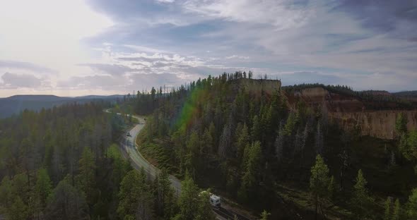 Aerial video as cars drive along a winding highway near green pines (Zion National Park, Utah) alt