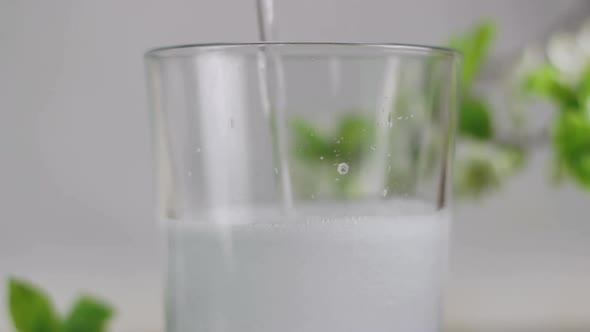 Pouring cold transparent carbonated soft drink into glass, green background alt