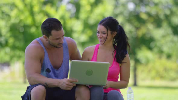 Athletic couple at park use laptop computer