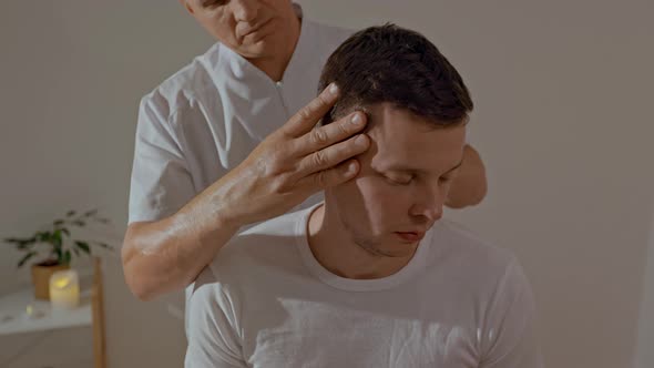 Young Man Relaxing During Professional Head Massage in SPA Salon