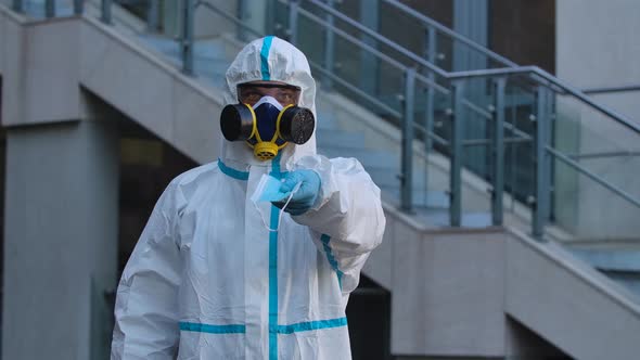 Portrait of a Young Man in a Protective Suit, Respirator, Gloves and Safety Glasses Looks Into the alt