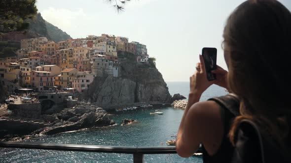 Girl Using Cell Phone Photography App in the City Manarola Italy.