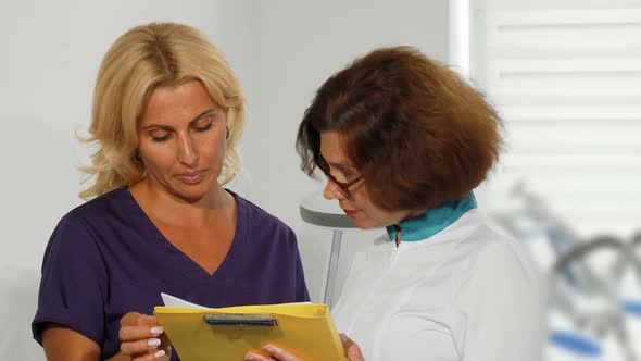 Female Doctors Examining Medical Survey Documents at the Clinic 1080p alt