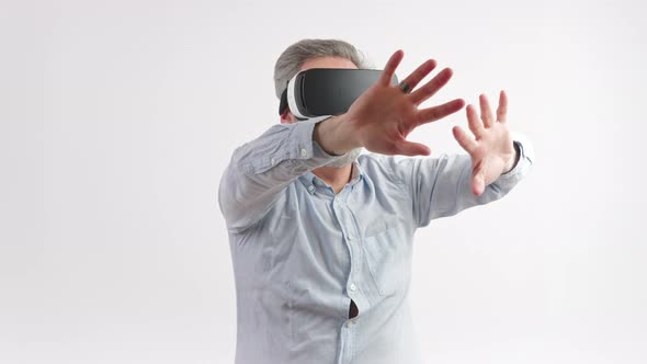 50s Greyhaired Man Moves His Hands Wearing Vr Goggles Studio Shot Medium Shot White Background alt
