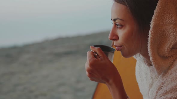 Closeup Portrait of Confident Pretty Woman Sitting at Tent Entry and Holding Mug with Coffee in Hand alt