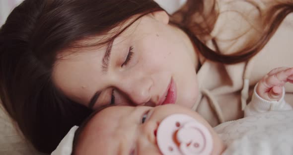 Mom Lies On The Bed Next To The Baby And Calms Him Down