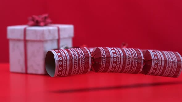 Christmas cracker dropping and bouncing beside present and decorations alt