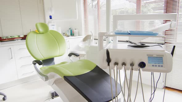 Empty interior of dental clinic with green dental chair and tools alt