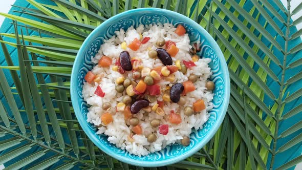Bowl Of Rice With Legumes On Green Leaves And Blue Background