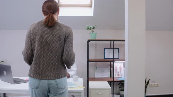 Doctor Sees Patient Looking at Xrays Wearing Medical Gown and Stethoscope alt