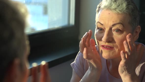 Senior Female Looking at Sagging Skin Face in Mirror Old Age Appearance alt