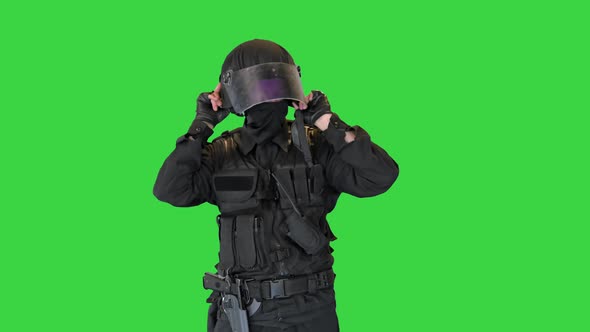 Police Officer in Full Protection Riot Gear Putting on Helmet on a Green Screen Chroma Key alt