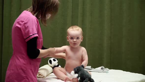 The masseuse gives a massage of shoulder to baby (boy) 03 alt