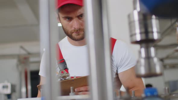 Young Man Worker of Water Factory Checking Quality and Making Inspection in Line Production