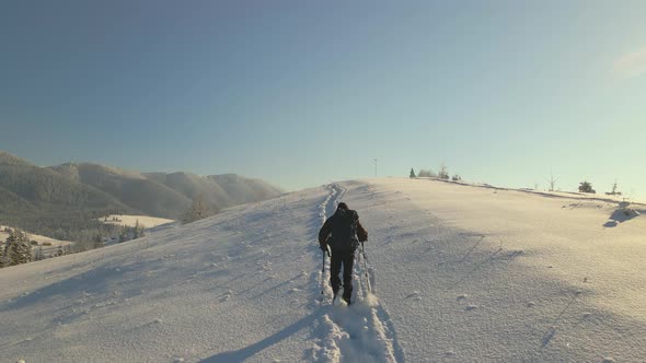 Hiker with Backpack Walking on Snowy Mountain Hillside on Cold Winter Day alt