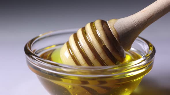 fresh golden honey pours beautifully from a wooden honey spoon