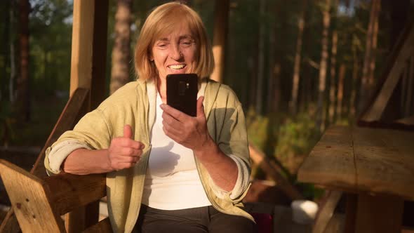 Attractive Happy Senior Elderly Woman Having Video Chat Outdoors Waving
