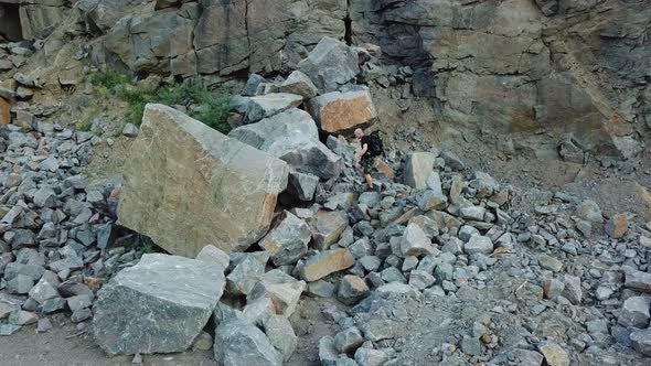 Man Walking Along Giant Rocky Mountain Wall alt