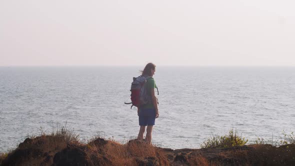 Back View Portrait of Tourist Backpacker Standing at Sea Ocean Background Copy Space. Man Hiker alt