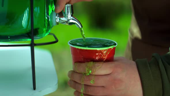 Pouring of Green Lemonade in a Plastic Cup in Slow Motion