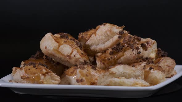 Baked puff pastry with toppings. Puffs with cheese on white plate rotating in front of camera alt