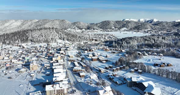 Aerial view of snow covered Bakuriani with beautiful snowy mountains around. Georgia 2021 alt