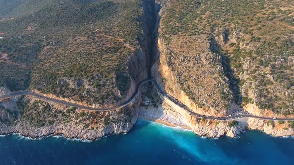 People Swim on Light Blue Sea in the White Sandy Beach Near the Rocky Mountainside alt