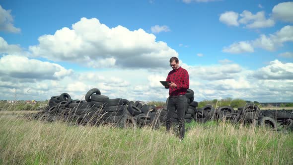 Inspector Records Pollution Level on Tire Dump. Ecology Pollution Concept. Recycled Tire Pile. Old alt