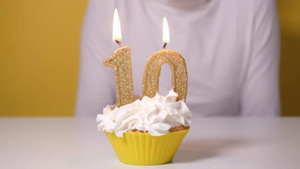 Happy Teen Girl Blowing Out Number 10 Candle on Birthday Cake at Party